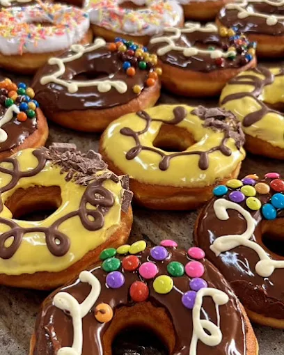 A tray of fresh donuts glazed in chocolate and custard yellow, topped with sprinkles and sweets