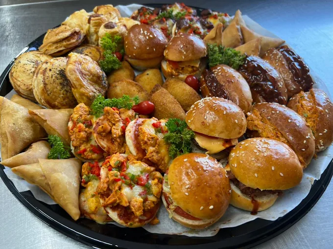 A loaded platter of samoosas, pies, mini burgers, spring rolls and chicken bites